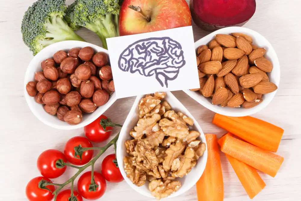 Variety of fruits and vegetables arranged around a brain chart showing natural sources of vitamins and minerals that boost memory and focus.